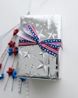 a wrapped box in silver foil stars and stars and stripes ribbon