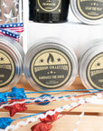 three candle tins with decorative red white and blue stars next to them