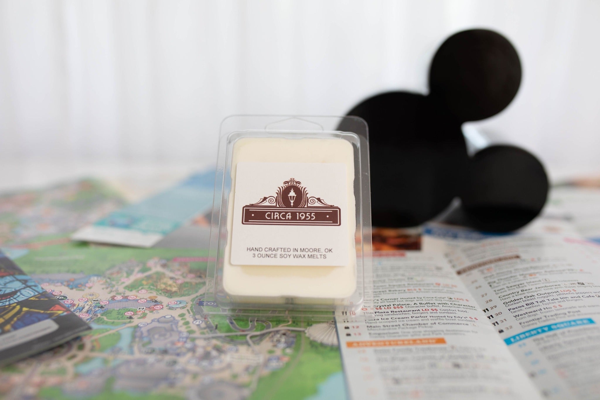 A plastic, six-cavity clamshell melt sitting on top of a map of Disneyland with a black mickey head icon in the background.