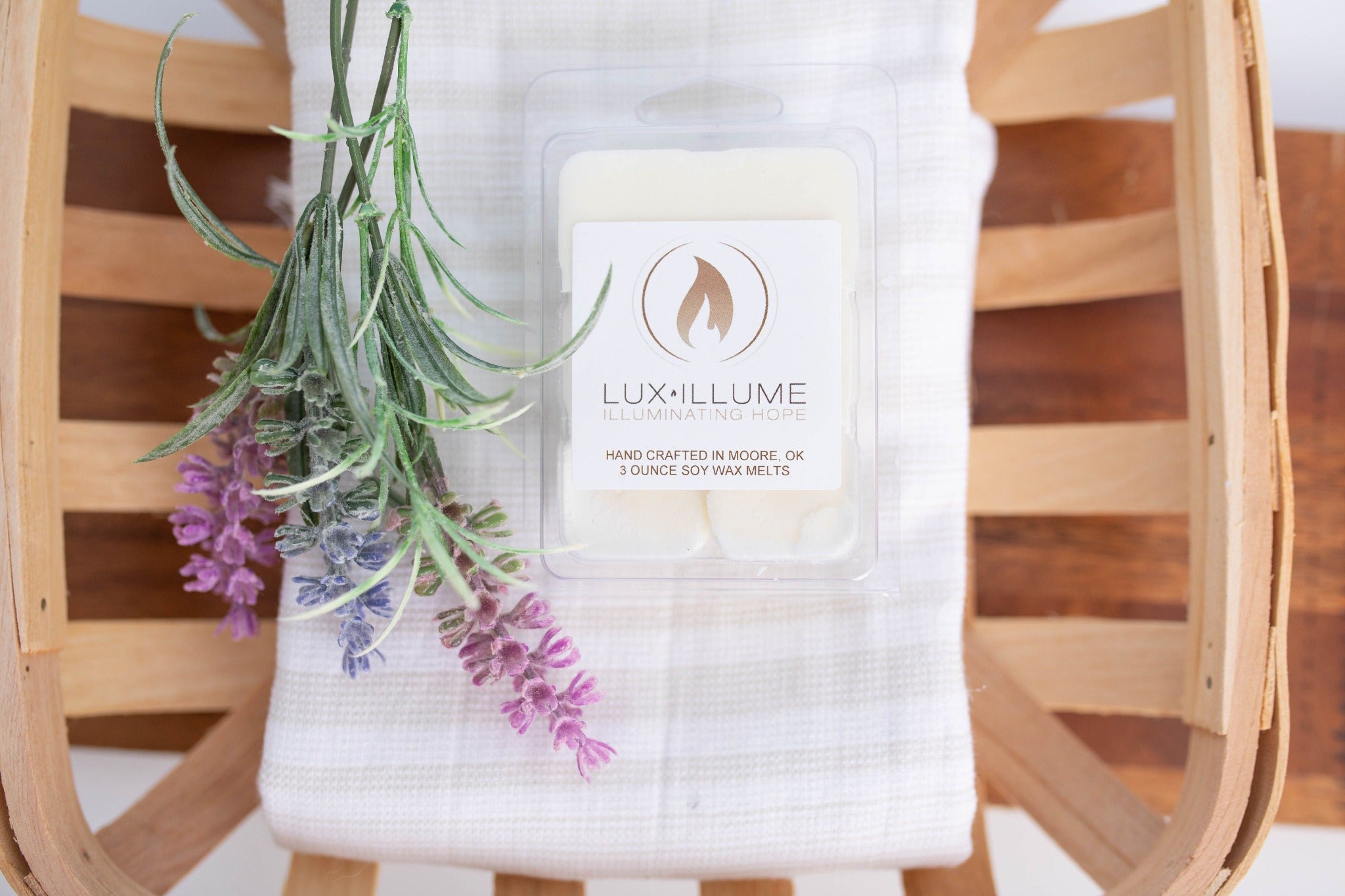 A plastic, six-cavity clamshell melt in a wood basket with a linen towel and small bunch of lavender next to it.