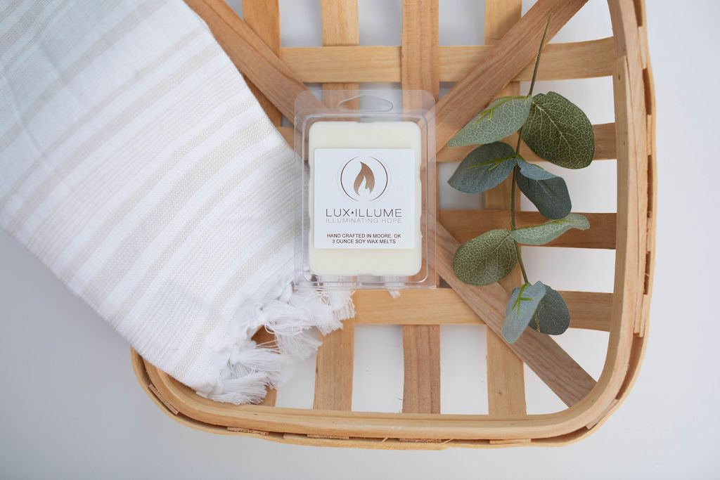 A plastic, six-cavity clamshell melt in a wood basket with a linen towel and small branch of eucalyptus leaves next to it.