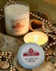 a glass candle and a silver candle tin surrounded by gold beads and pirate treasure