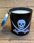 a black glass tumbler candle with the white jolly roger skull and crossed swords on it